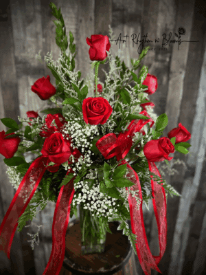 Elegant bouquet of red roses with green foliage and ribbons.