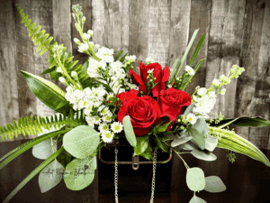A bouquet with red roses, white flowers, and green foliage.