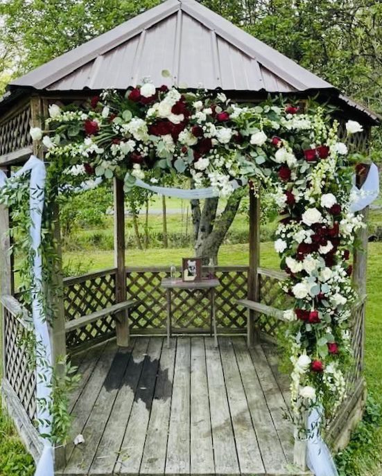 A gazebo decorated with lush floral arrangements and draped fabric.