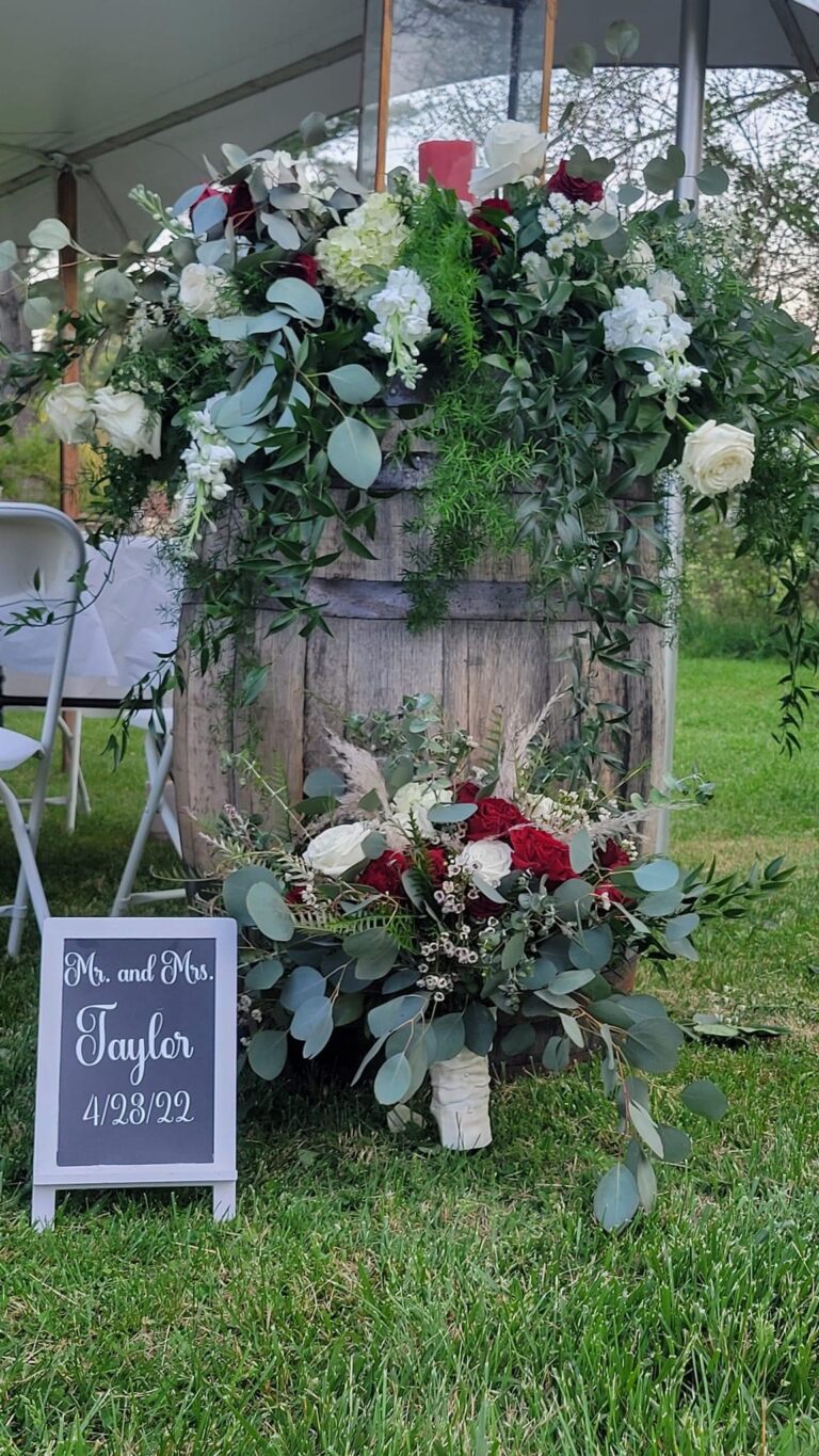 Rustic wedding sign and floral arrangement beside wooden door.