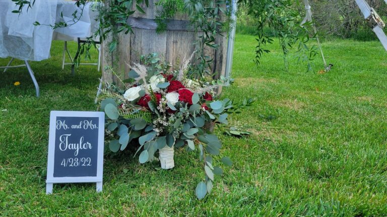 Rustic wedding bouquet with red and white flowers on grass.