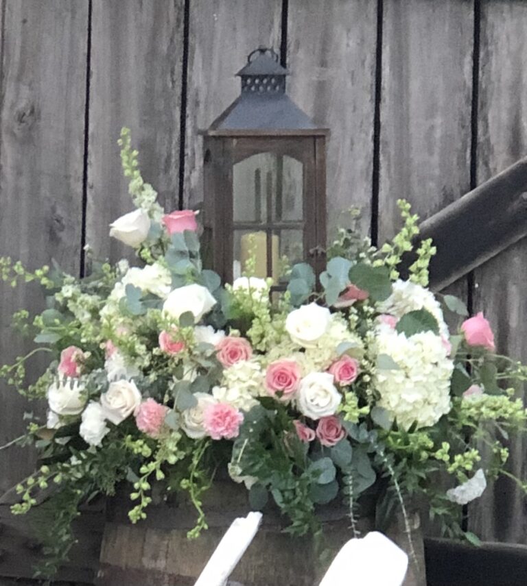 Elegant floral arrangement with pink and white flowers around a lantern.