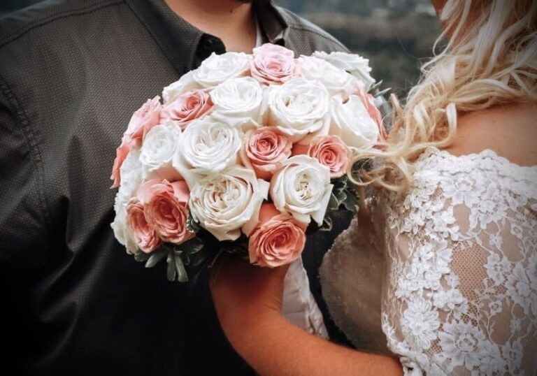 A bride holding a bouquet of pink and white roses.