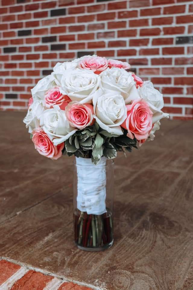 Elegant bouquet of white and pink roses wrapped in white ribbon.