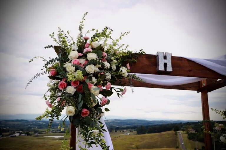 Rustic wedding arch adorned with vibrant flowers and greenery.