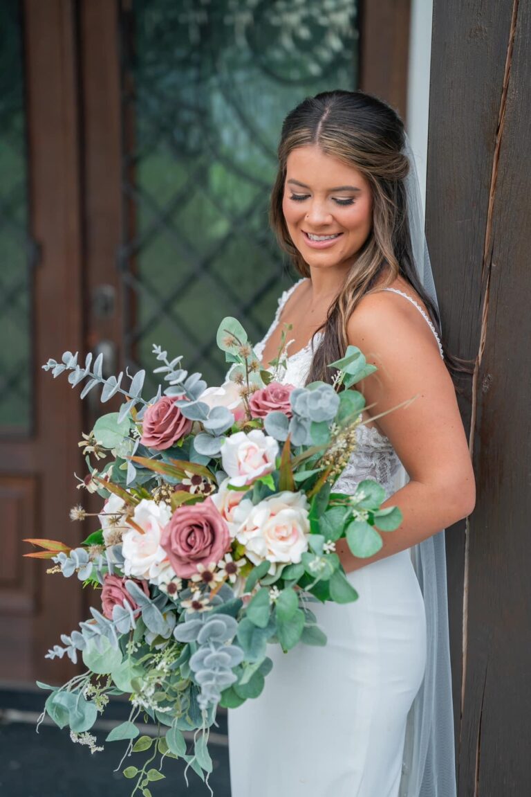 Bride holding a large, elegant bouquet with pastel flowers and greenery.