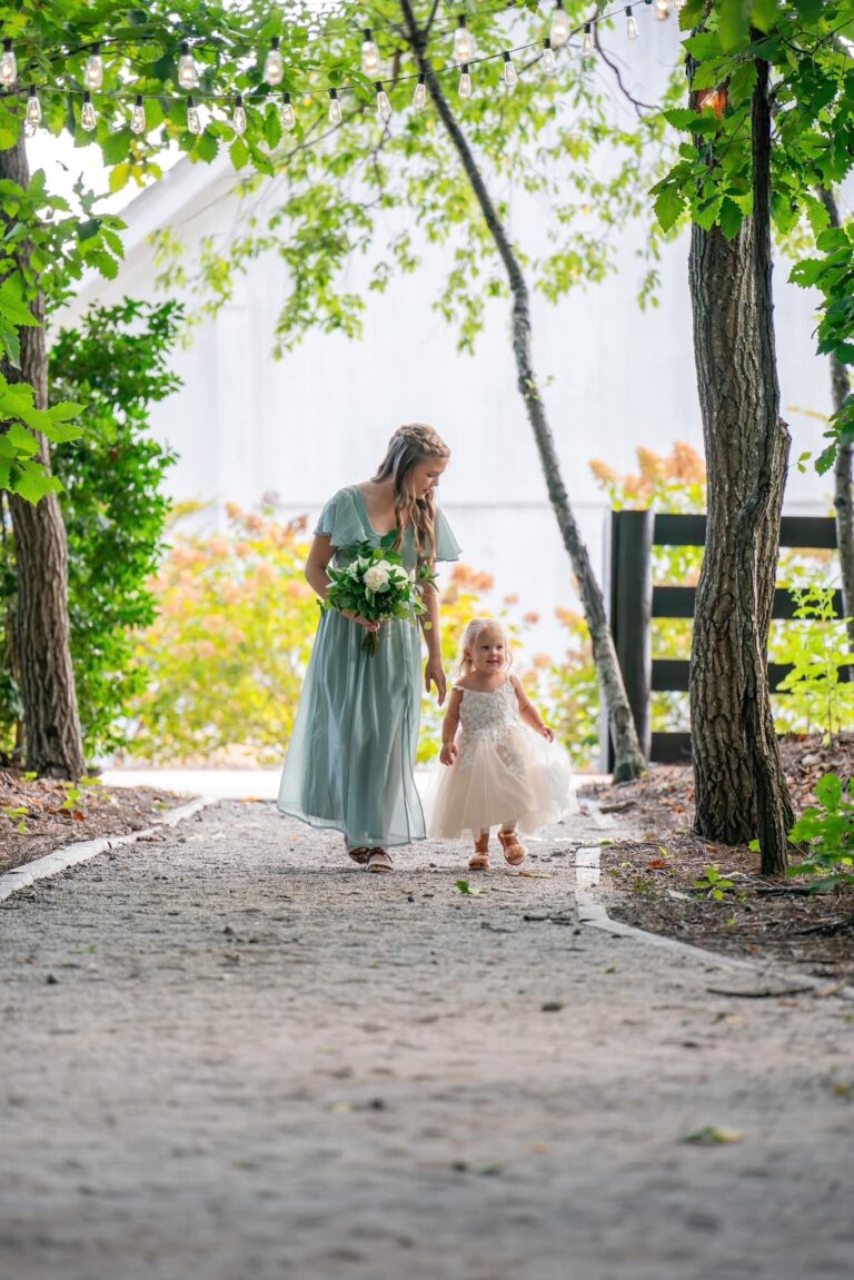A woman and a little girl walking hand in hand on a garden path.