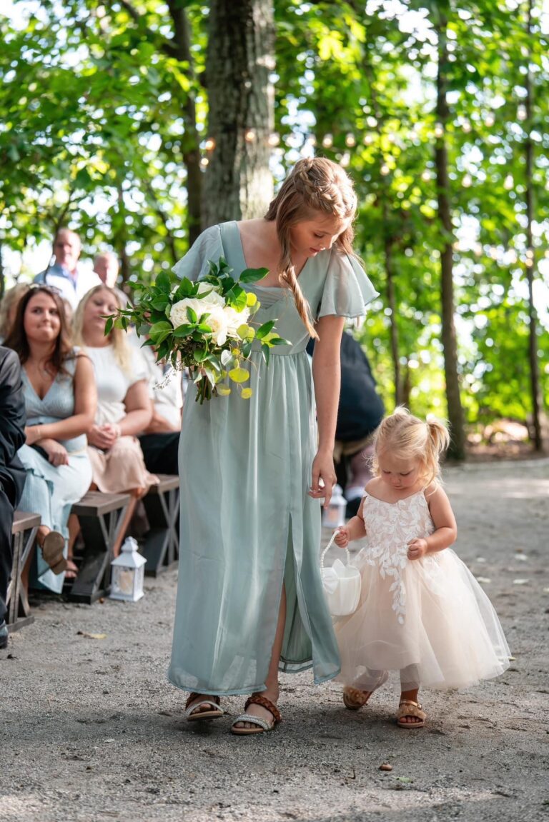 A woman in a light blue dress holding a toddler's hand at an outdoor event.