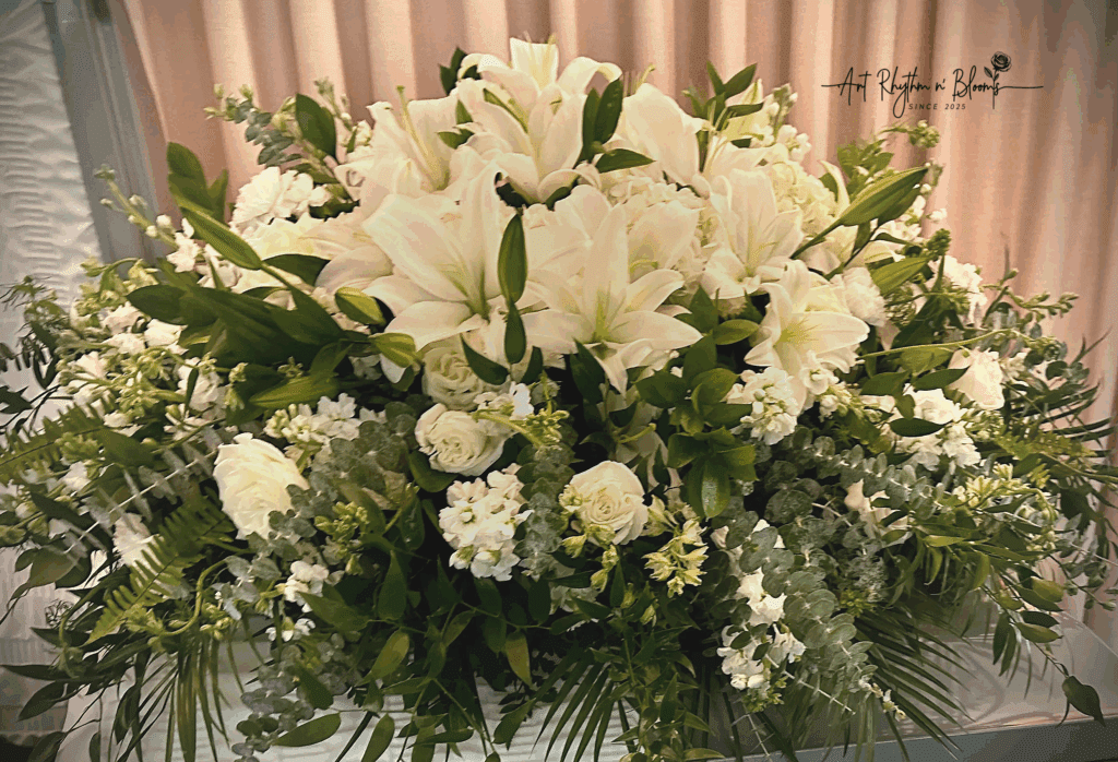 Elegant white floral arrangement with lilies and greenery.