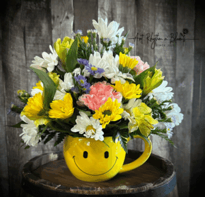 Bright yellow smiley face mug with a cheerful mixed flower bouquet.