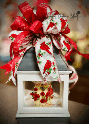 A festive white lantern adorned with Christmas-themed ribbons and decorations.
